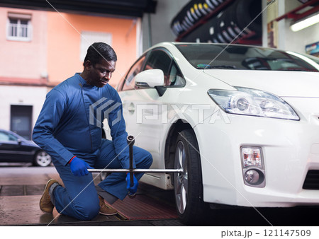 African american car mechanic screwing the wheel African american car mechanic screwing the wheel 121147509