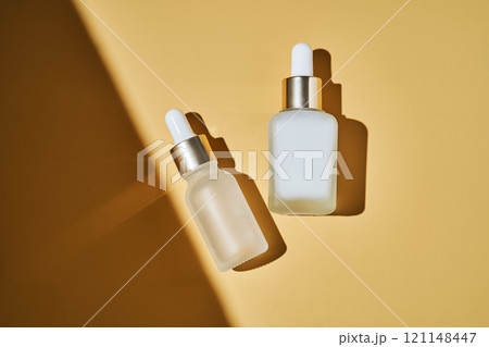 Two bottles of serum on a beige background with a beautiful shadow. 121148447