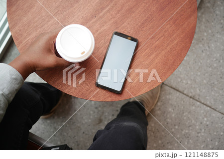 Enjoy a Relaxing Coffee Break while Using a Smartphone on a Wooden Table Surface 121148875