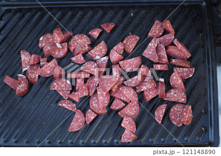 Grilled Salami Slices Arranged Beautifully on the Cooking Surface for a Savory Delight 121148890