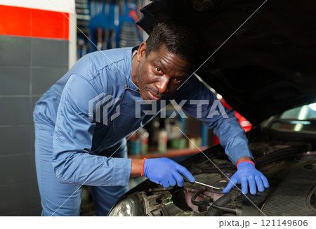 Professional american mechanic man in uniform repairing car engine Professional american mechanic man in uniform repairing car engine 121149606