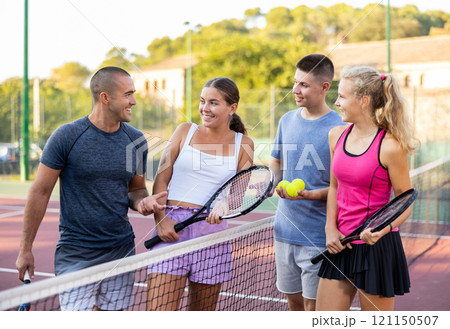 Two pairs of tennis players are happily discussing past game on an open court Two pairs of tennis players are happily discussing past game on an open court 121150507