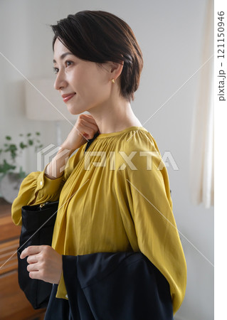 屋内でバッグとジャケットを持つ女性 121150946
