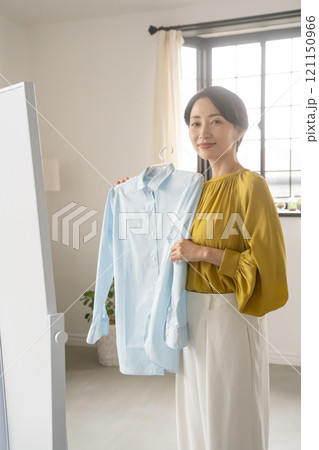 部屋で洋服を選ぶ女性 121150966