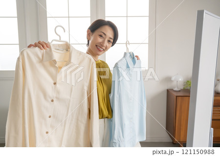 部屋で洋服を選ぶ女性 121150988