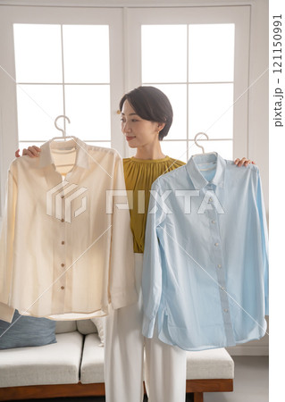 部屋で洋服を選ぶ女性 121150991