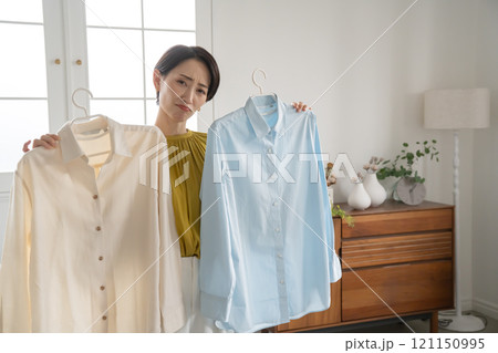 部屋で洋服を選ぶ女性 121150995