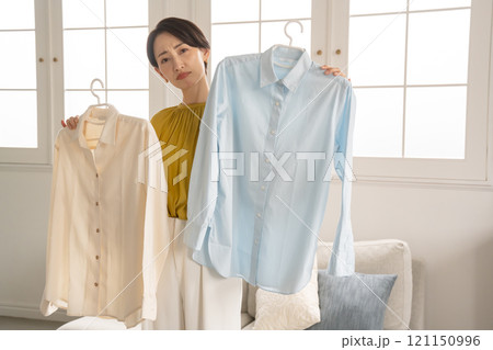 部屋で洋服を選ぶ女性 121150996