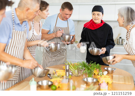 Young woman teaching group of people how to cook 121151259