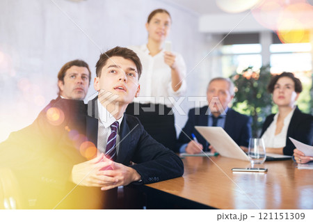 Focused colleagues of different ages discussing ideas and watching presentation while gathering in meeting room Focused colleagues of different ages discussing ideas and watching presentation while gathering in meeting room 121151309