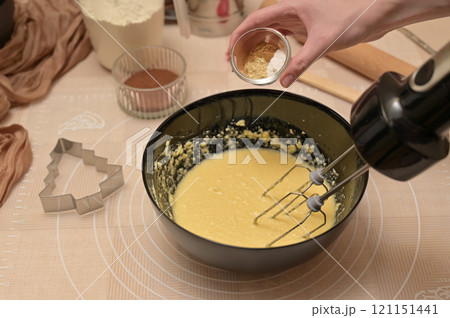 Christmas homemade baking, ingredients for baking gingerbread, woman adding spices to dough in black bowl 121151441