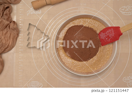 Christmas homemade baking, ingredients for baking gingerbread, silicone spatula in a white bowl with cocoa and flour, tree shaped cutter and rolling pin 121151447