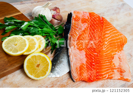 Raw salmon fillet on wooden table with condiments Raw salmon fillet on wooden table with condiments 121152305