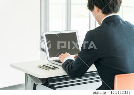 ノートパソコンを使い仕事する若いアジア人ビジネスマン男性の後ろ姿 ノートパソコンを使い仕事する若いアジア人ビジネスマン男性の後ろ姿 121152332