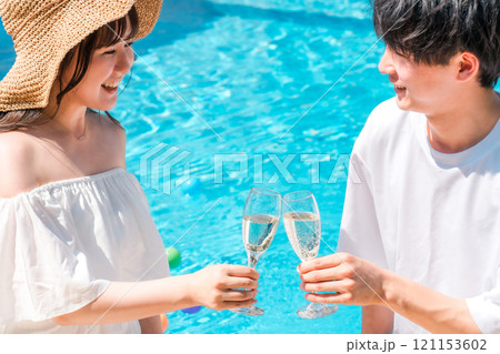 バカンス・リゾートホテルのプールサイドでシャンパングラスで乾杯するカップル 121153602