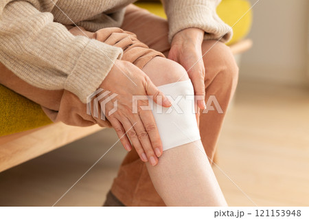 膝に湿布を貼るミドル〜シニア女性 膝に湿布を貼るミドル〜シニア女性 121153948