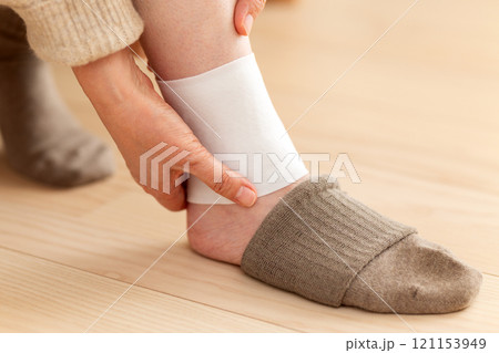 足首に湿布を貼るミドル〜シニア女性 121153949