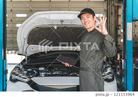 タブレットを使って自動車のエンジルームをチェックする自動車整備士の男性メカニック タブレットを使って自動車のエンジルームをチェックする自動車整備士の男性メカニック 121153964
