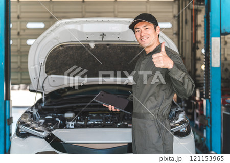タブレットを使って自動車のエンジルームをチェックする自動車整備士の男性メカニック 121153965