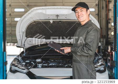 タブレットを使って自動車のエンジルームをチェックする自動車整備士の男性メカニック タブレットを使って自動車のエンジルームをチェックする自動車整備士の男性メカニック 121153969