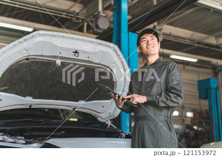 タブレットを使って自動車のエンジルームをチェックする自動車整備士の男性メカニック タブレットを使って自動車のエンジルームをチェックする自動車整備士の男性メカニック 121153972