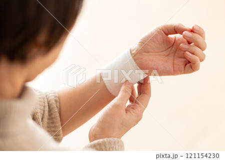 包帯が巻かれた手首を押さえるミドル〜シニア女性 121154230