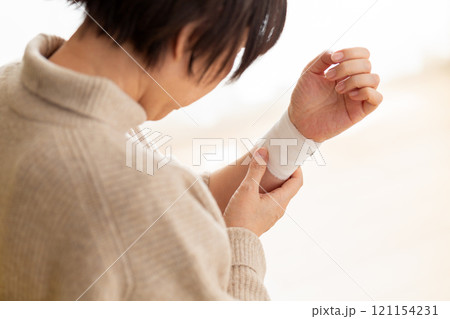 包帯が巻かれた手首を押さえるミドル〜シニア女性 121154231