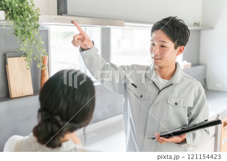 換気扇・レンジフードの説明を受ける主婦の女性と工務店・設備屋・電気工事士・業者の作業着姿の男性 換気扇・レンジフードの説明を受ける主婦の女性と工務店・設備屋・電気工事士・業者の作業着姿の男性 121154423
