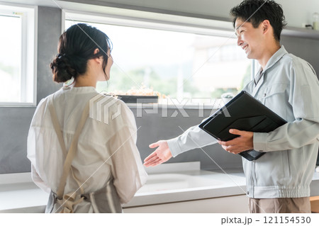 キッチンで主婦に水道屋・設備の説明をする水道屋・設備屋の男性 121154530