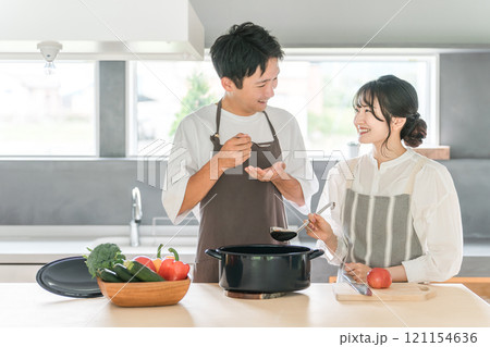 料理を作って味見をする夫婦・カップル・男女(キッチン) 料理を作って味見をする夫婦・カップル・男女(キッチン) 121154636