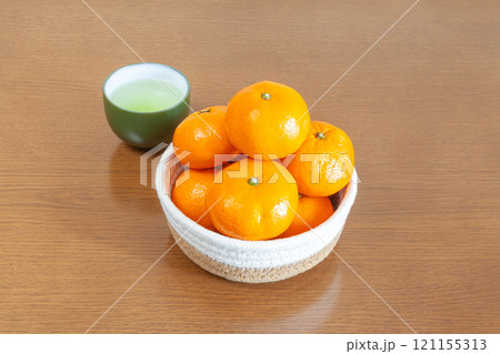コタツのテーブルに置かれたカゴ盛りミカンと日本茶 コタツのテーブルに置かれたカゴ盛りミカンと日本茶 121155313