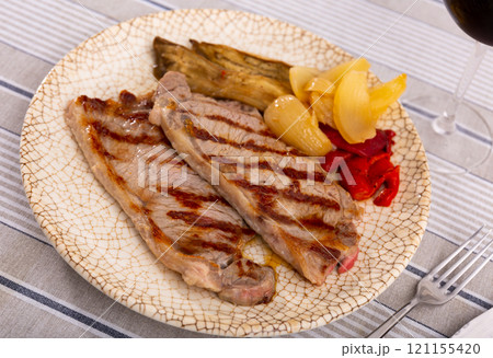 On plate two pieces of barbecue beef with fried vegetables - eggplant slices and green bell peppers 121155420