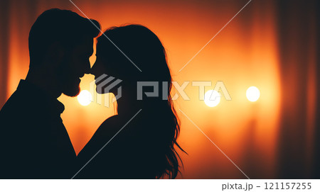 Silhouette of couple in dimly lit room with warm lighting 121157255