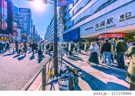 日本の東京都市景観 師走。低く横切る太陽光や長い影、池袋駅東口…円陣を組む人達…。希望の光＝7日 121159866