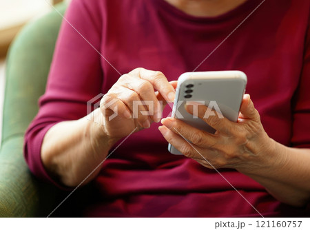 スマホを操作するワインレッドのカットソーを着た70代の女性 スマホを操作するワインレッドのカットソーを着た70代の女性 121160757