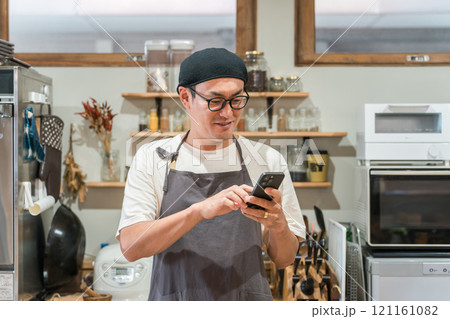 カフェ・レストラン・飲食店で働くウェイトレス・ホールスタッフをする男性(スマホ・モバイルオーダー) カフェ・レストラン・飲食店で働くウェイトレス・ホールスタッフをする男性(スマホ・モバイルオーダー) 121161082