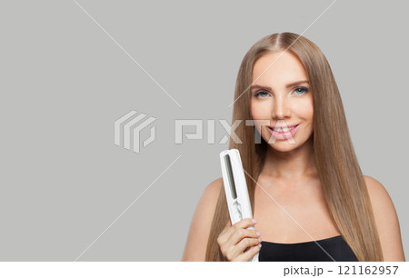 Glad brunette lady with straight hair holding straightening iron on white background.  121162957
