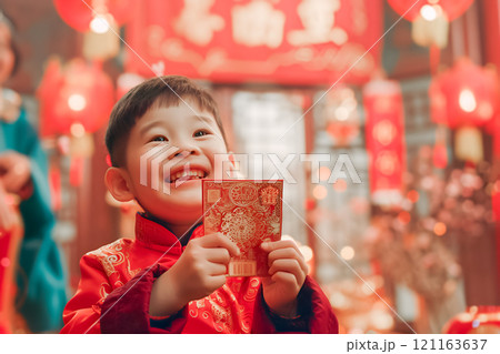 A smiling child eagerly holding up a Hong Bao envelope 121163637