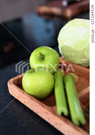 Celery, apples and cabbage are on board in kitchen. Vegetables and fruits for vegetarian dish or side dish. Celery, apples and cabbage are on board in kitchen. Vegetables and fruits for vegetarian dish or side dish. 121164526