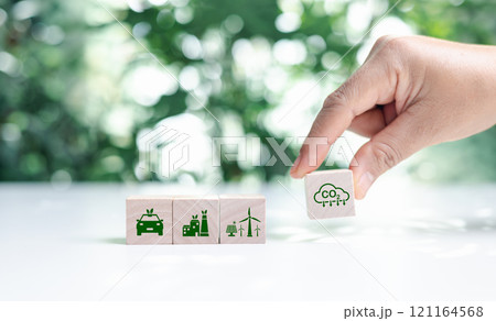 Hand put wooden cubes with green net zero icon and green icon on bokeh nature. Net zero and carbon neutral concept. Net zero greenhouse gas emissions target. Climate neutral long term strategy. Hand put wooden cubes with green net zero icon and green icon on bokeh nature. Net zero and carbon neutral concept. Net zero greenhouse gas emissions target. Climate neutral long term strategy. 121164568
