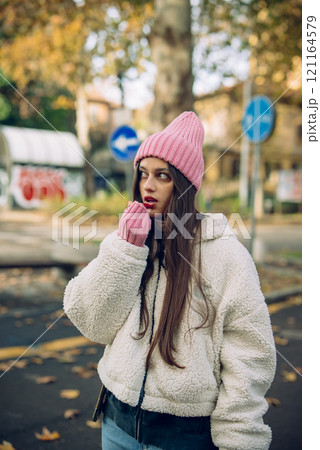 A Young Woman Wearing Cozy Winter Attire Enjoys the Outdoors in a Picturesque Setting 121164579