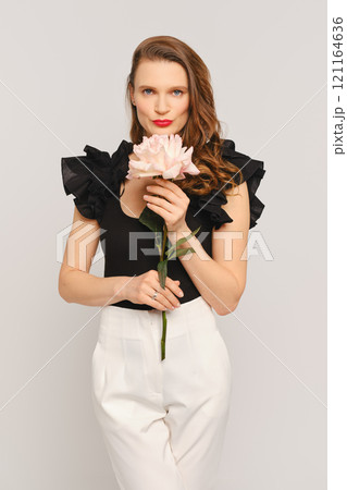 Model with flower poses elegantly in contemporary fashion studio setting 121164636