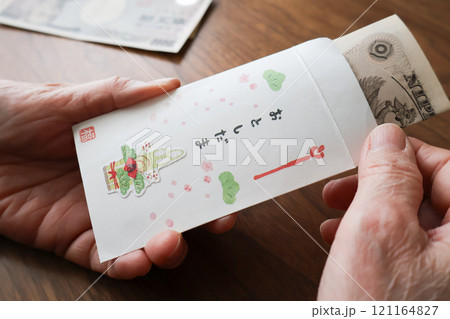 お年玉袋に紙幣を入れるシニア女性の手元 121164827