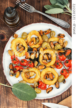 Grilled mussels with herbs and squid rings. 121165372