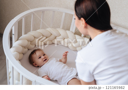 mother takes care of her child, puts him to sleep in a crib mother takes care of her child, puts him to sleep in a crib 121165982