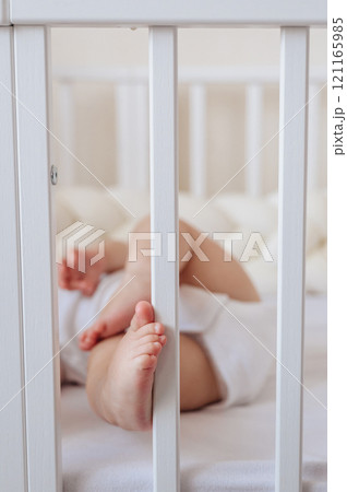 little baby lying in bed in bright room, cute baby feet 121165985