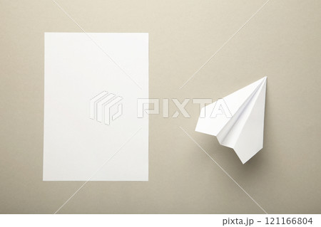 Flat lay of white paper plane and blank paper on grey background Flat lay of white paper plane and blank paper on grey background 121166804