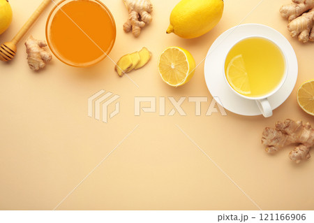 Ginger tea with lemon in a white cup on beige background. 121166906