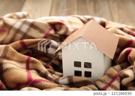 House in winter - heating system concept and cold snowy weather with model of a house with plaid 121166930
