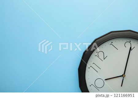 Black wall clock on the blue background. 121166951